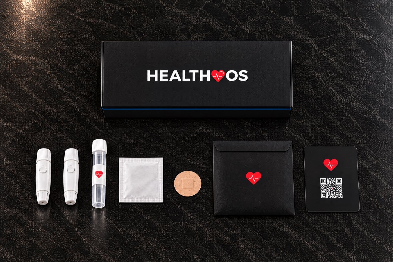 Seen from above on dark marble: the closed black HealthOS box, and below it lancets, a small collection tube, an alcohol pad, a plaster, a black envelope and a black card with a QR code
